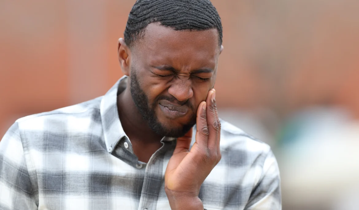 Front view portrait of a man with black skin complaining about tooth ache