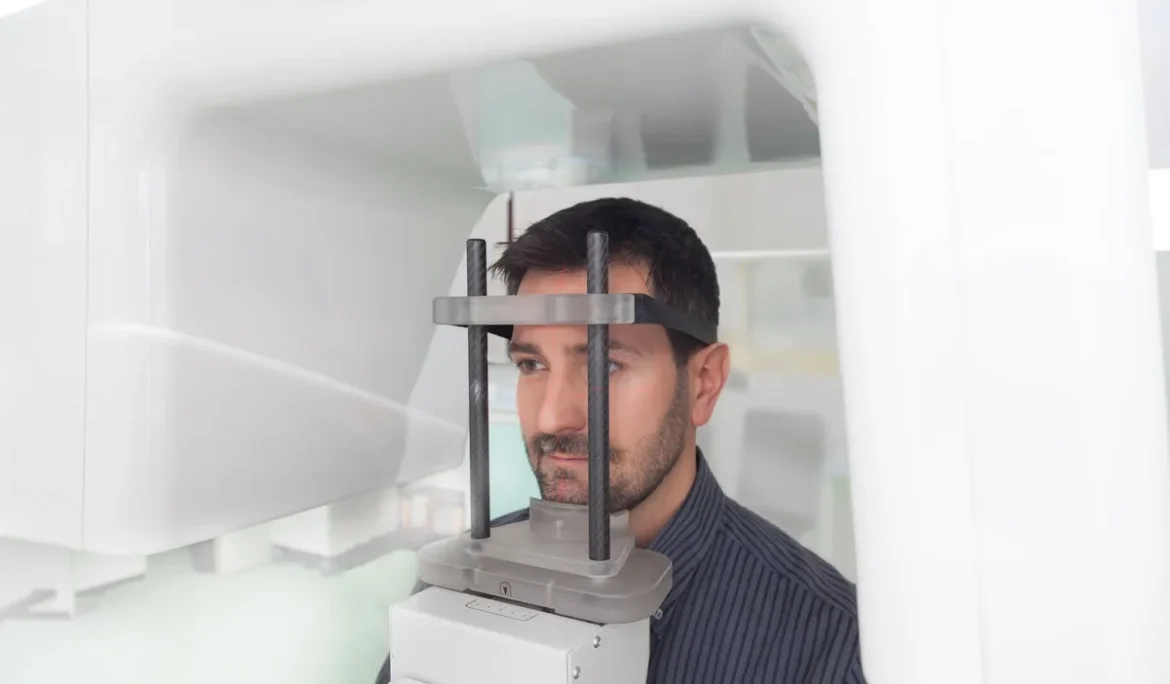 Young man portrait having panoramic digital X-ray of his teeth in the dental office.