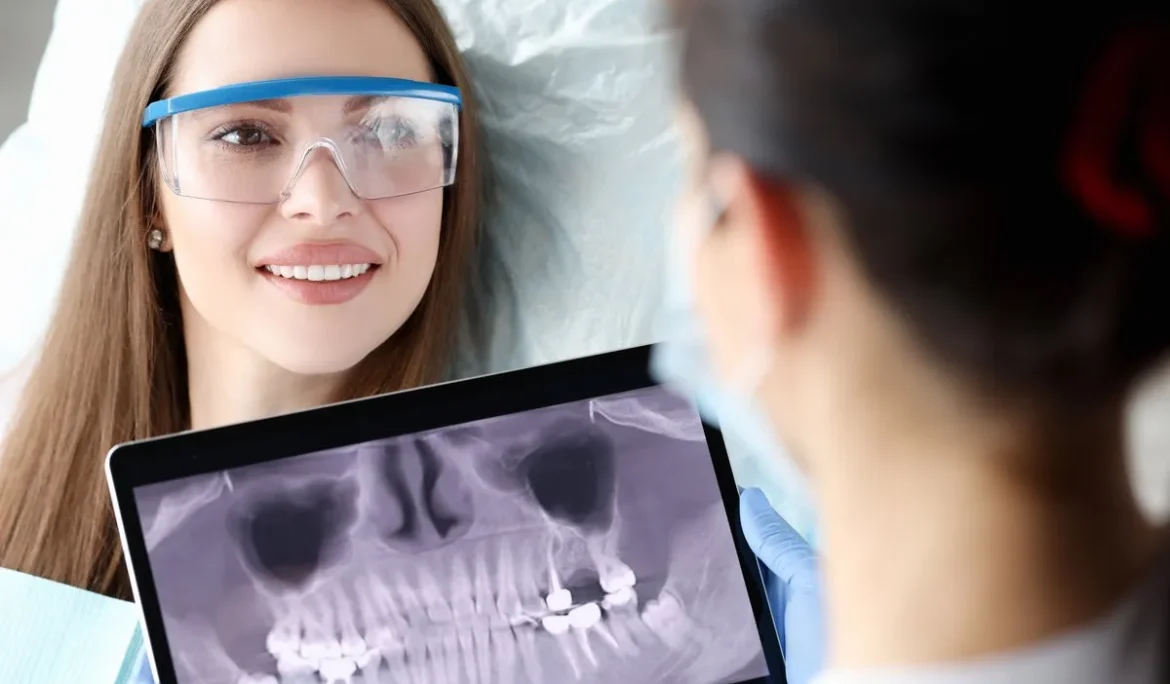 Dentist holding digital tablet with 3D picture of teeth in hands in front of female patient. Dental implantation concept